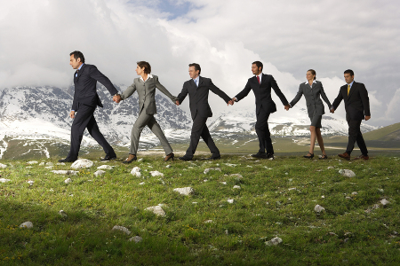 Side view of business people holding hands and walking through m